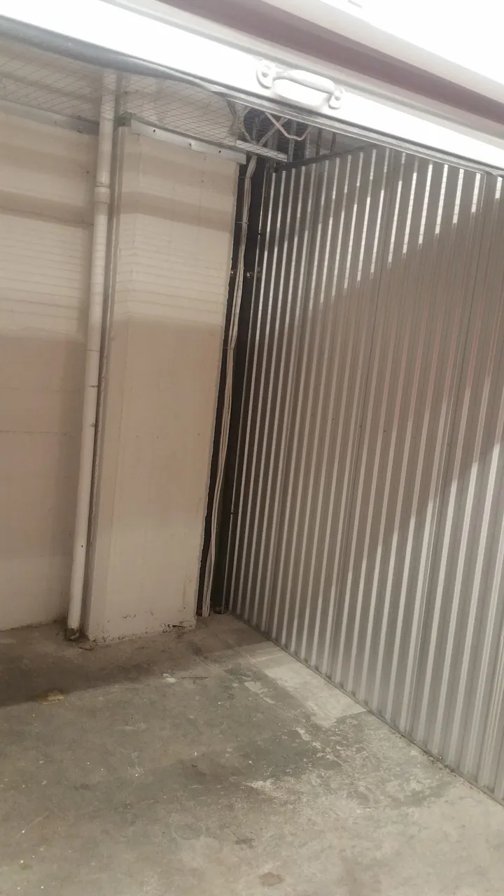 Interior view of an empty storage unit with corrugated metal wall.