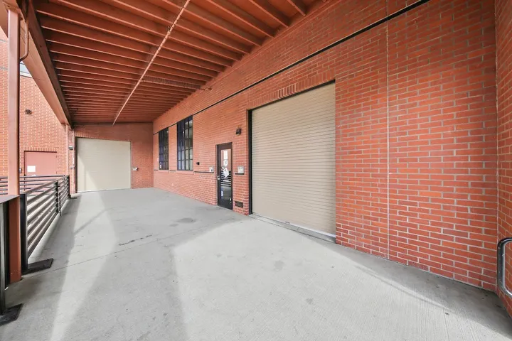 Covered outdoor hallway with roll-up doors to storage units.