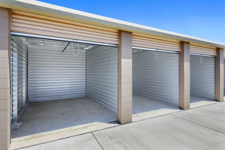Multiple open outdoor storage units with roll-up doors.