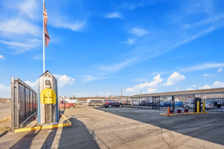 Outdoor parking lot with a security gate entrance and guard statue.