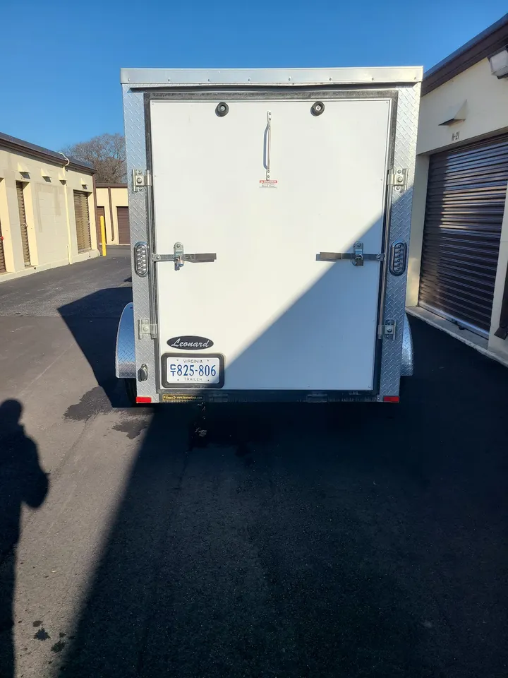 Small utility trailer parked outside units.