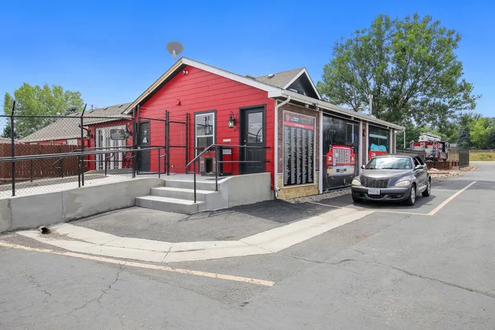 Exterior of the leasing office with a parked car and ramp.