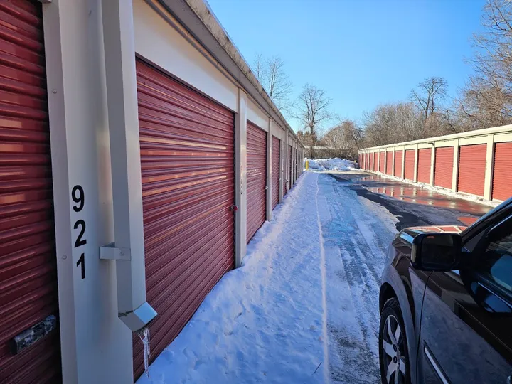 Drive-up storage units with red doors overlooking snow on ground