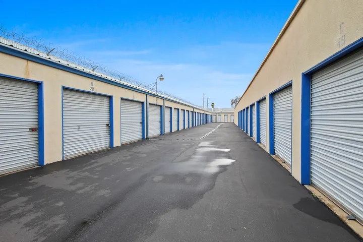 Long row of drive-up storage units with security fencing at a facility.