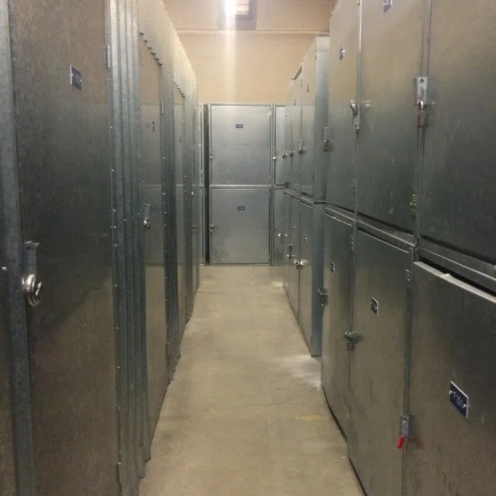 Indoor concrete hallway lined with rows of locked metal storage units and smaller stacked lockers