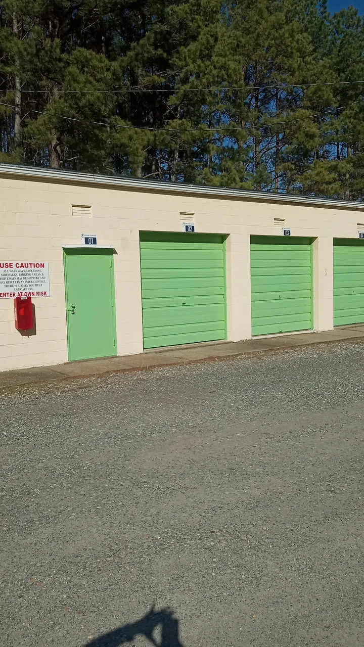 Exterior of storage units with green roll-up doors.