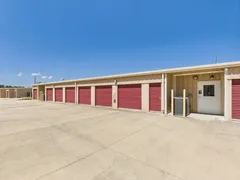 Exterior view of a drive-up storage building featuring red roll-up doors and a white service entrance