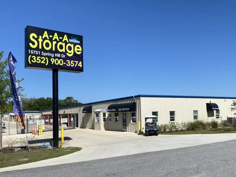 Large A-A-A Storage sign in front of a tan rental office with black awnings and a gate
