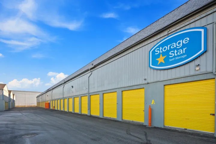 Exterior view of a gray storage building with yellow roll-up doors and a blue Storage Star sign