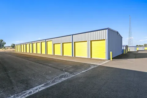 Outdoor storage building featuring a row of yellow roll-up doors and a wide paved driving aisle