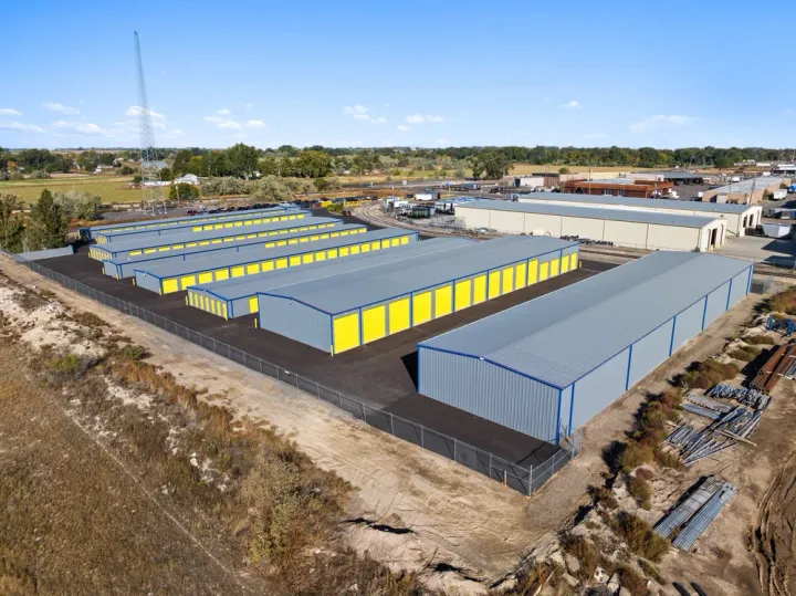 Aerial view of several long rows of self-storage units with yellow doors and metal roofs