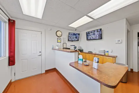 A brightly lit rental office featuring a service counter, security monitor screens, and a white entry door at Storage Star Self-Storage in Laramie, WY