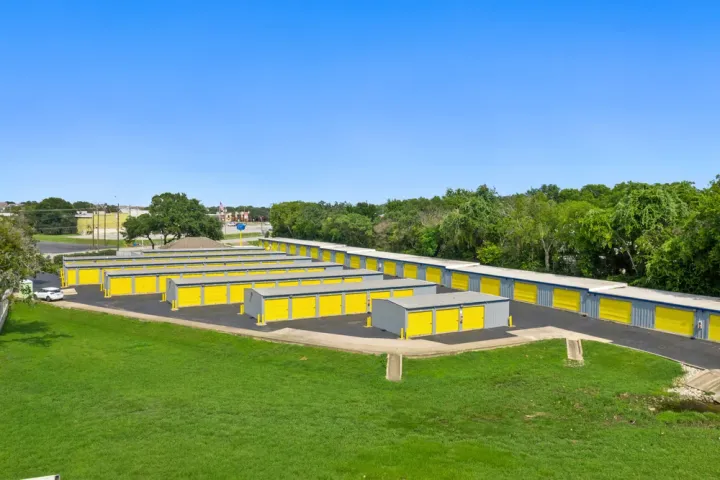 Aerial view of multiple drive-up self-storage buildings with yellow roll-up doors and paved drive aisles